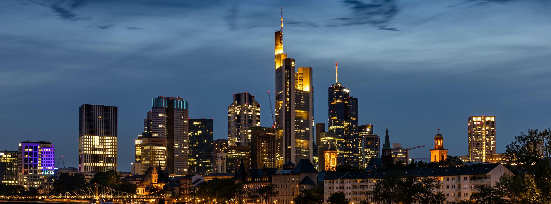 Frankfurt am Main bei Nacht: beleuchtete Skyline mit Wolkenkratzern und weiteren Gebäuden