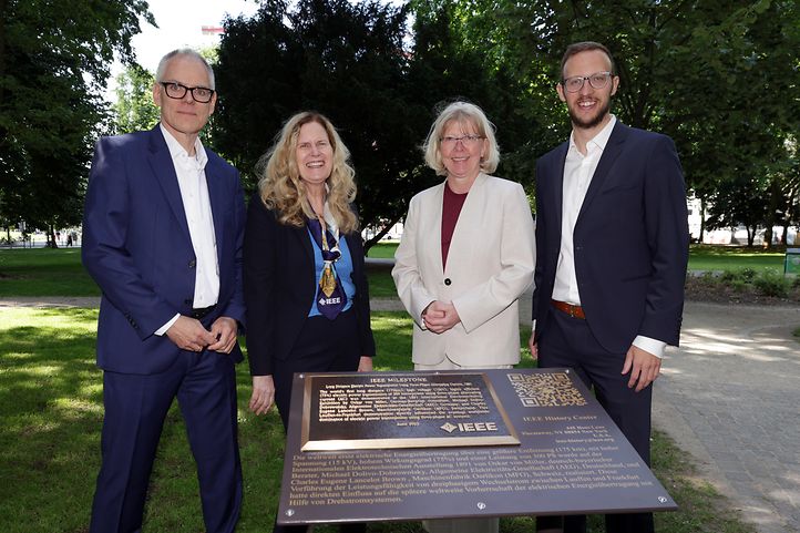 Vier Menschen in einem park vor einer Gedenktafel