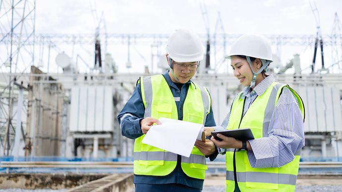 Zwei Arbeiter vor einer Umspannanlage 
