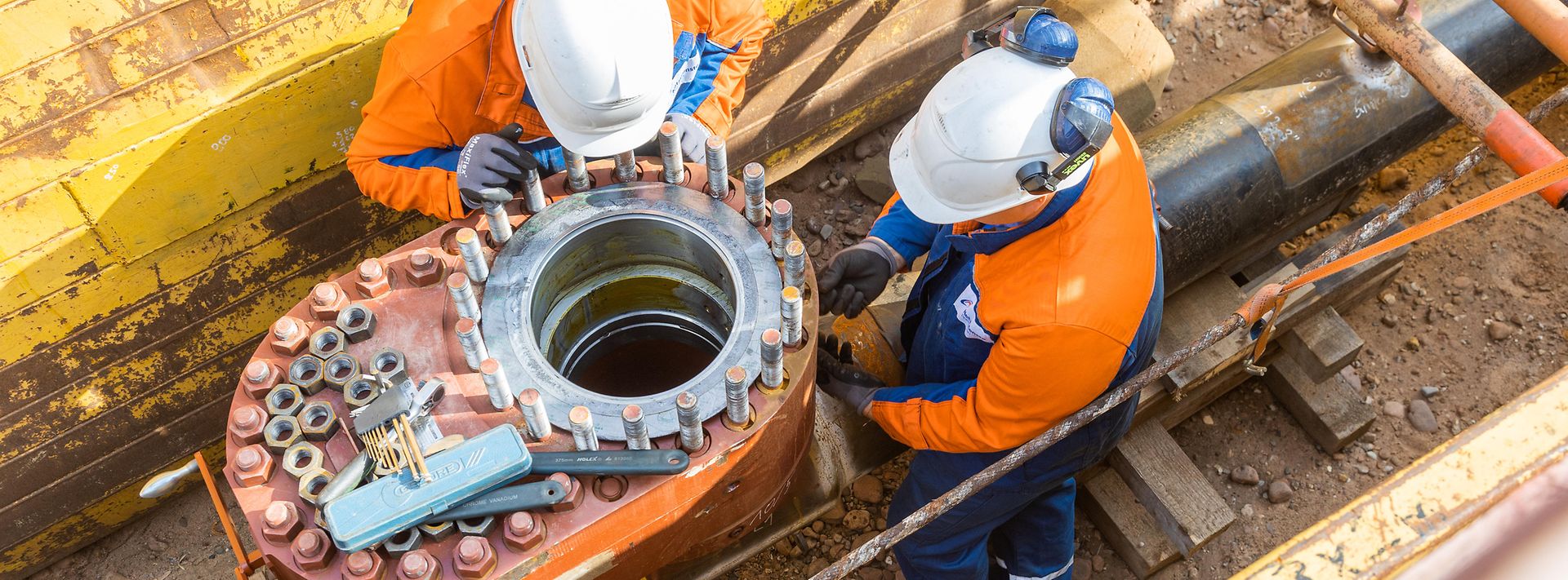 2 Personen im Arbeitsgraben mit Helmen und Arbeitshandschuhen