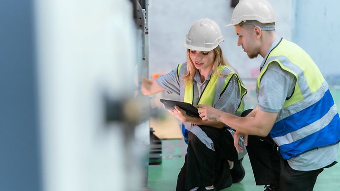 Männliche und weibliche Techniker inspizieren Maschinen in einem Lager