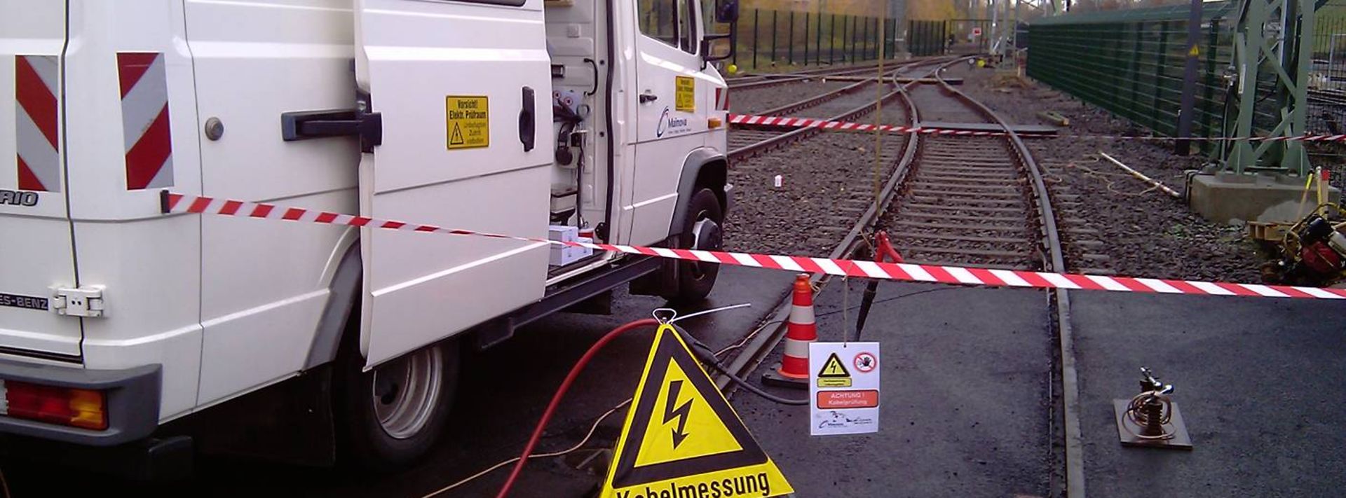 Abgesperrte Kabelmessung an Bahngleisen mit Servicefahrzeug und Warnschild.